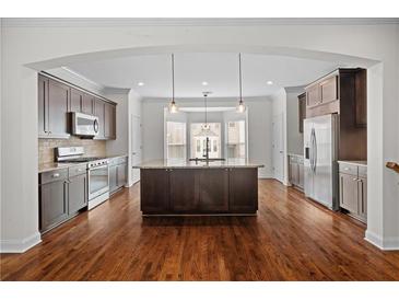 Open kitchen featuring dark wood cabinetry, stainless steel appliances, and a large center island at 2171 W Village Se Ln, Smyrna, GA 30080