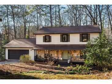Charming two-story home featuring a stone porch, attached garage, and a serene wooded setting at 4568 Oswood Ct, Tucker, GA 30084