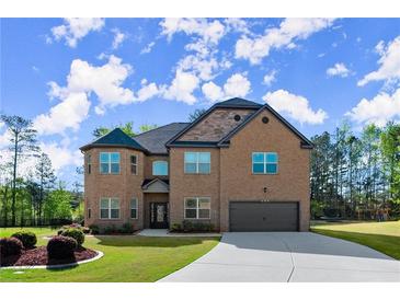 Elegant two-story brick home featuring a manicured lawn, attached garage, and driveway at 404 Prague Way, Hampton, GA 30228
