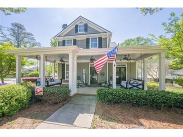 Charming two-story home featuring a covered porch with swing seating and manicured landscaping at 498 Trip St, Grayson, GA 30017