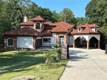 Stunning home featuring a tile roof, arched entryway, and lush landscaping at 725 Links View Dr, Sugar Hill, GA 30518