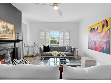 Inviting living room with a cozy fireplace, grey sofa, and bright natural light from the window at 108 Vinings Forest Se Cir, Smyrna, GA 30080