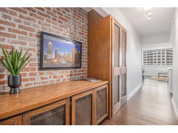 Hallway with exposed brick wall, wooden storage, and view of city buildings through the window at 215 Piedmont Ne Ave # 1110, Atlanta, GA 30308