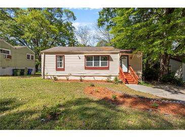 Charming tan home featuring a well maintained lawn and complemented by mature trees at 2383 Baker Nw Rd, Atlanta, GA 30318