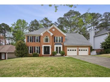 Traditional brick home featuring a well-manicured lawn, a two-car garage, and classic architectural details at 4284 Windy Gap Nw Ct, Kennesaw, GA 30144