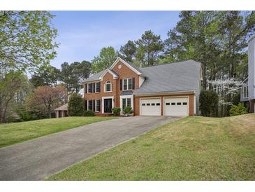 Beautiful brick home with a two-car garage and long driveway, surrounded by lush trees and greenery at 4284 Windy Gap Nw Ct, Kennesaw, GA 30144