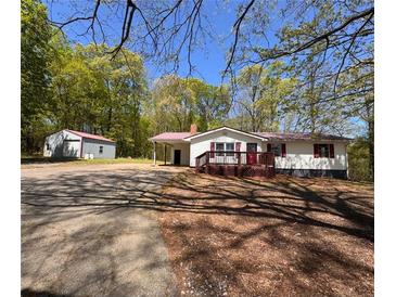 Charming single-story home with white siding, a cozy front porch, and a detached garage at 5130 English Dr, Cumming, GA 30041