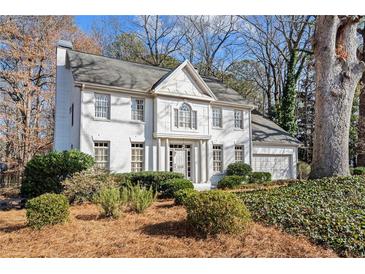 Beautiful two-story home featuring a white brick facade, landscaped front yard, and attached two-car garage at 2125 Fairfax Dr, Alpharetta, GA 30009