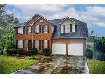 Charming two-story brick home with a two-car garage and well-manicured lawn at 2121 Silva Ct, Conley, GA 30288