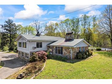 Charming home featuring stone accents, a metal roof, and a lush green lawn at 700 Stewart Rd, Covington, GA 30016