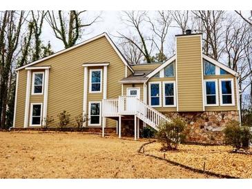 Charming home featuring large windows, white trim, stone accents, and a welcoming entryway staircase at 5035 Post Road Ct, Stone Mountain, GA 30088