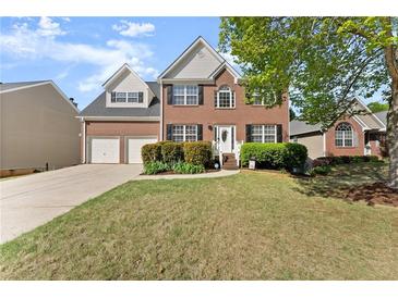 Charming two-story brick home with a well-manicured lawn, attached two-car garage, and inviting front entrance at 3978 Oak Crossing Drive Dr, Suwanee, GA 30024
