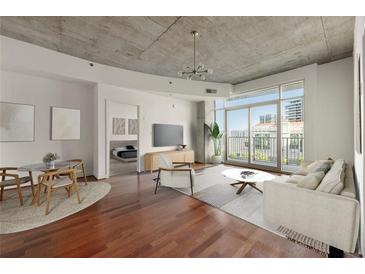 Bright living room with hardwood floors, modern lighting, and sliding glass doors to a balcony at 250 Pharr Ne Rd # 905, Atlanta, GA 30305