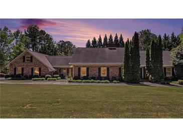 Charming brick home with well-manicured lawn, mature trees, and dusk sky for a warm, inviting feel at 1935 Northbrooke Ln, Atlanta, GA 30338