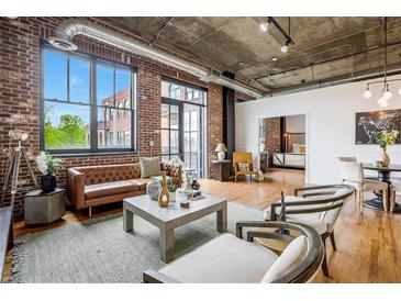Bright living room features exposed brick, concrete ceilings, stylish furniture, and large windows at 3235 Roswell Ne Rd # 721, Atlanta, GA 30305