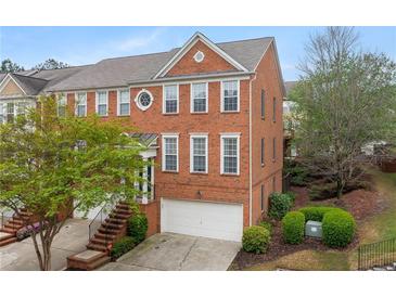 Lovely exterior elevation of a red brick townhome with an attached garage and well-maintained landscaping at 4880 Payson Se Ter, Atlanta, GA 30339