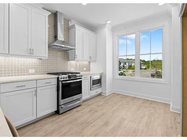 Bright kitchen boasts white cabinetry, stainless steel appliances, and a large window with neighborhood views at 2842 Evanshire Ave # 113, Duluth, GA 30096