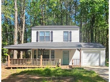 Charming two-story home with a covered front porch and attached garage is surrounded by mature trees at 4460 Branchwood Ct, Loganville, GA 30052