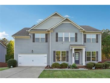 Charming two-story home with gray siding, a well-manicured lawn, and an attached two-car garage at 4528 Venus Sw Ct, Powder Springs, GA 30127