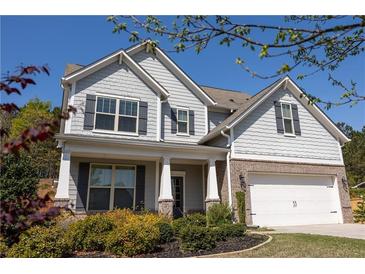 Charming two-story home featuring a brick-accented garage, gray siding, and a well-manicured front yard with mature landscaping at 2034 W Hampton Dr, Canton, GA 30115