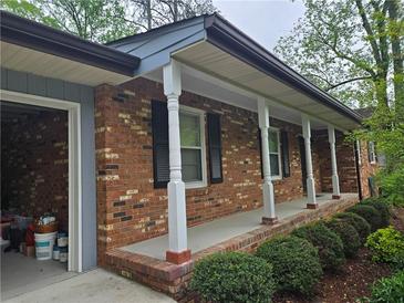 Charming brick home featuring a covered front porch with elegant white columns and black shutters at 1089 Seven Springs Cir, Marietta, GA 30068