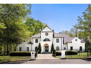 Stunning white home with manicured landscaping and black trim, enhanced by a wrought iron fence and mature trees at 725 Riley Pl, Atlanta, GA 30327