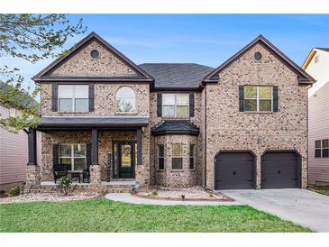 Charming two-story brick home with a well-manicured lawn and inviting front porch at 1023 Bentley Estates Dr, Dacula, GA 30019
