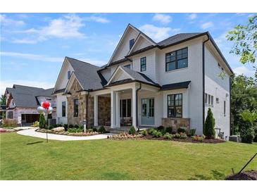 Beautiful two-story home featuring a stone and white brick facade, manicured lawn, and inviting front porch at 4976 Concert Ln, Marietta, GA 30066