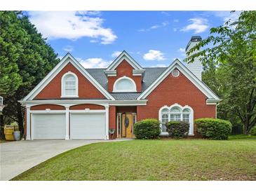 Charming brick home with a two-car garage and a well-manicured front lawn under a partly cloudy sky at 4505 Lakefield Bnd, Berkeley Lake, GA 30096