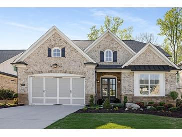 Charming, light brick home featuring a two-car garage and a beautifully landscaped front yard at 3825 Raeburn Rd, Cumming, GA 30028