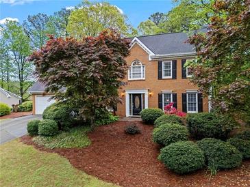 Charming brick home featuring a manicured lawn and mature trees surrounding the property at 5663 Brookstone Nw Dr, Acworth, GA 30101