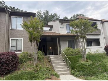 Two-story condo unit features a well-maintained landscaped entrance and multiple windows for natural light at 323 Seasons Pkwy, Norcross, GA 30093