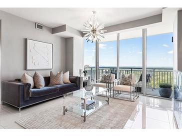 Bright living room with floor-to-ceiling windows and balcony access, showcasing a modern chandelier and stylish decor at 3338 Peachtree Ne Rd # 3102, Atlanta, GA 30326