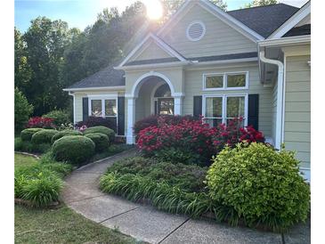 Charming single-story home featuring a landscaped front yard with flowering bushes, lush plants and a winding walkway at 59 Sentry Rdg, Dallas, GA 30157