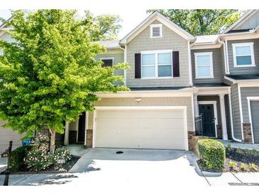 Charming townhome featuring an attached garage, neutral colors, and a beautiful landscaped yard with flowering plants at 1058 Mays Sw Hl, Atlanta, GA 30336