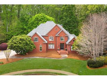 Elegant two-story red brick home with a well-manicured lawn and lush, mature landscaping at 221 Streamside Ct, Lilburn, GA 30047