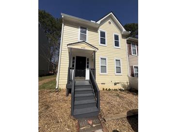 Charming two-story home with pale yellow siding, black front door, and inviting covered porch at 4049 Heritage Valley Ct, Norcross, GA 30093