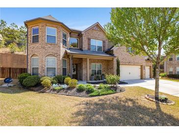 Inviting two-story brick home featuring a landscaped front yard and a three-car garage at 4015 Two Bridge Ct, Buford, GA 30518