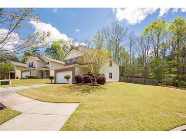 Charming two-story home with a well-manicured lawn, attached garage, and beautiful landscaping at 6884 Barker Station Walk, Sugar Hill, GA 30518