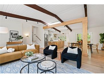 Bright living room with wood beam ceiling, modern furniture, and an open floor plan to the kitchen at 1690 Cotswold Ne Dr, Brookhaven, GA 30319