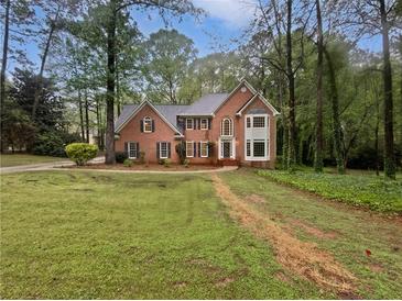 Beautiful brick home featuring a manicured lawn, mature trees and classic architectural details at 9174 Retreat Pass, Jonesboro, GA 30236