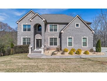 Charming grey brick home with manicured lawn and professional landscaping with mature trees at 3206 Letha Woods Dr, Conyers, GA 30094