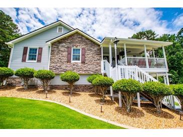 Charming home featuring a stone facade, a welcoming front porch, and meticulously manicured landscaping at 84 Ledbetter Rd, Villa Rica, GA 30180