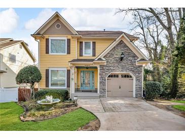 Charming two-story home with a stone accent garage, a manicured lawn, and a welcoming, light blue front door at 1093 Third St, Stone Mountain, GA 30083