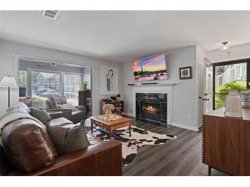 Cozy living room features a fireplace, hardwood floors, and large windows for natural light at 401 Berkeley Woods Dr, Duluth, GA 30096