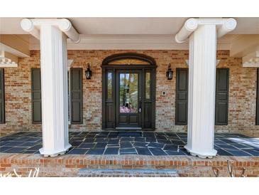 Elegant front entryway with a stylish door, decorative columns, and a brick facade at 6141 Windsong Way, Smoke Rise, GA 30087