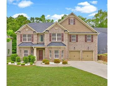 Traditional two-story brick home featuring a two-car garage, dormer, landscaped lawn, and symmetrical design at 5280 Clingman Ct, Douglasville, GA 30135