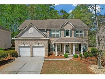 Charming two-story home features a two-car garage, brick facade, and beautifully landscaped front yard at 3447 Dogwood Pass, Lithonia, GA 30038