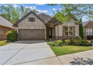 Charming brick and stone home with a two-car garage, manicured landscaping, and inviting curb appeal at 1227 Magnolia Path Way, Sugar Hill, GA 30518