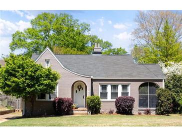 Charming home with a gray brick exterior, arched entryway, and a well-maintained front lawn at 812 E Ponce De Leon Ave, Decatur, GA 30030